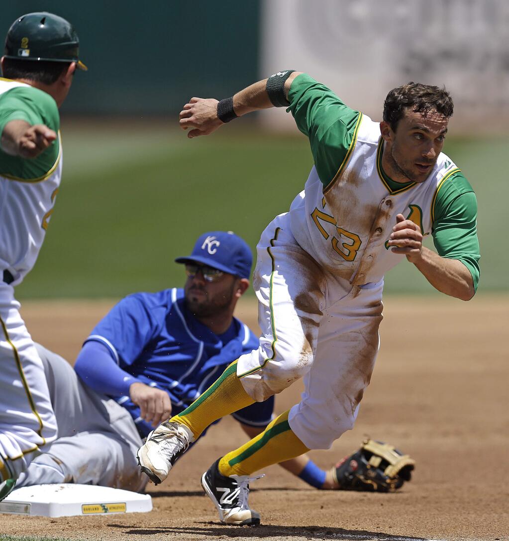 Oakland Athletics' Sam Fuld, right, runs to score past Kansas City Royals third baseman Mike Moustakas, center, in the first inning of a baseball game Saturday, June 27, 2015, in Oakland, Calif. Fuld scored after stealing third base on a throwing error by Royals' Chris Young. (AP Photo/Ben Margot)