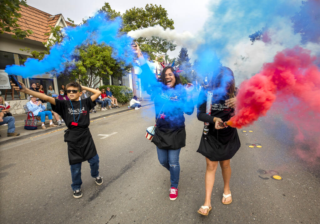 From left, Drake waters, Michel Schweikl and Maya McCutcheon create a patriotic smoke spectacle at the Cloverdale Fourth of July parade on the 150th anniversary of the founding of the town Monday, July 4, 2022. (John Burgess / The Press Democrat)
