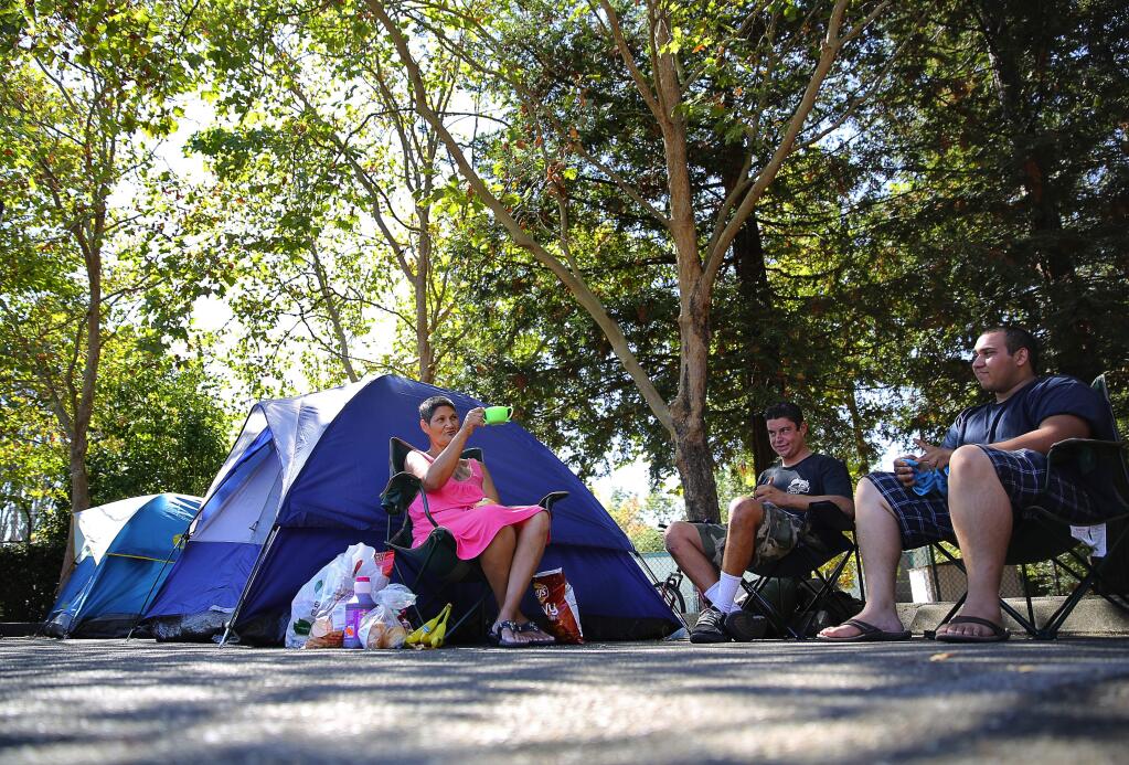 Roseanna Gonzalez, left, and her son, Junior Gonzalez, right, talk with Joshua Warner next to their tent at the homeless camp on county-owned property, that was formerly the Sonoma County Water Agency site on College Avenue, in Santa Rosa, on Tuesday, September 8, 2015. (Christopher Chung/ The Press Democrat)