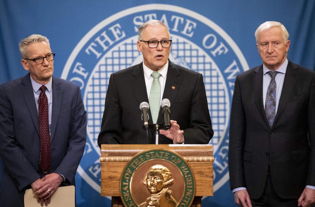 Washington Governor Jay Inslee gives updates on COVID-19 on Monday, March 2, 2020 in Olympia. Inslee declared a state of emergency in response to new cases of COVID-19 on Saturday. The governor was joined by Dr. John Wiesman, left, secretary of the Washington State Department of Health and Robert Ezelle, right, director of the Washington State Department of Emergency Management. (Amanda Snyder/The Seattle Times via AP)