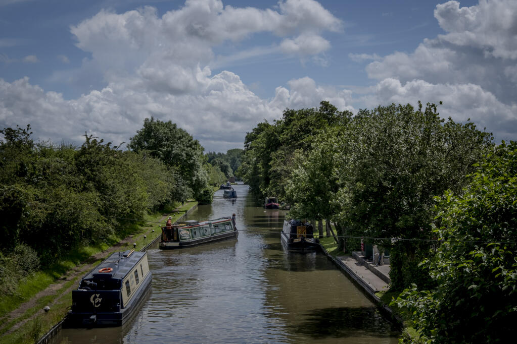 Canal boats on the Grand Union Canal near Daventry, England, on July 4, 2021. More people are calling England’s canals — and the narrow boats used to navigate them — home as remote work options in the pandemic’s wake make a mobile lifestyle more possible. (Andrew Testa/The New York Times)