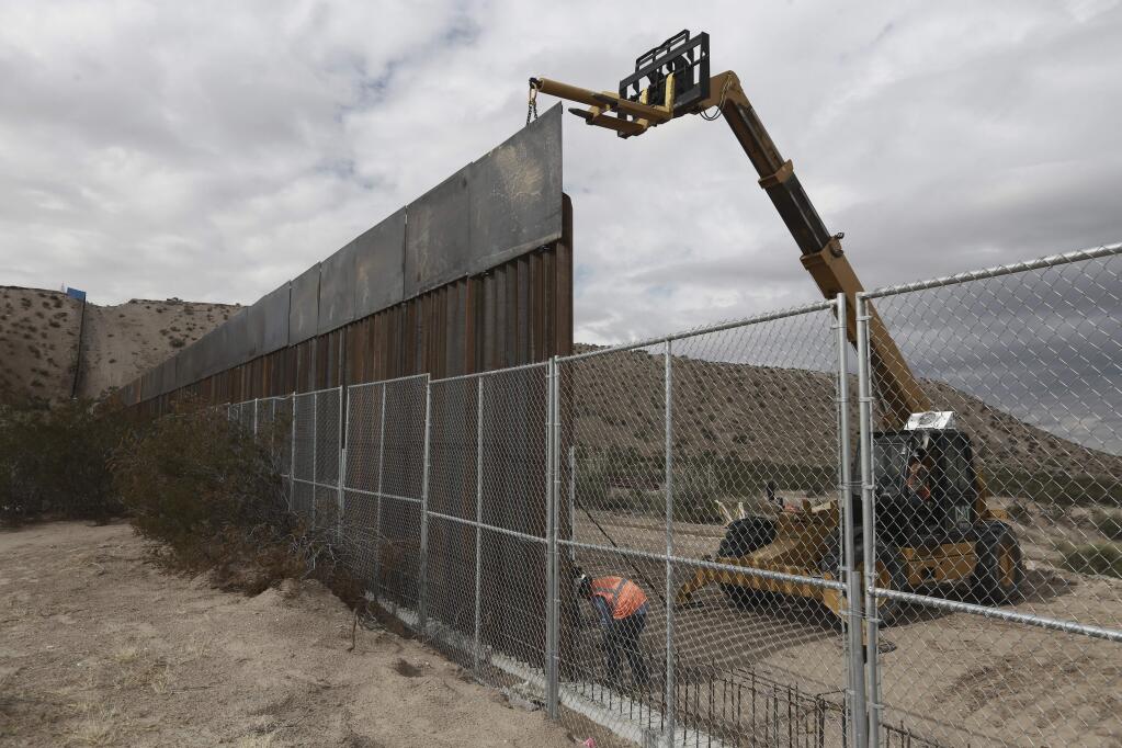 Workers raise a taller fence between the towns of Anapra, Mexico and Sunland Park, New Mexico in November. (CHRISTIAN TORRES / Associated Press)