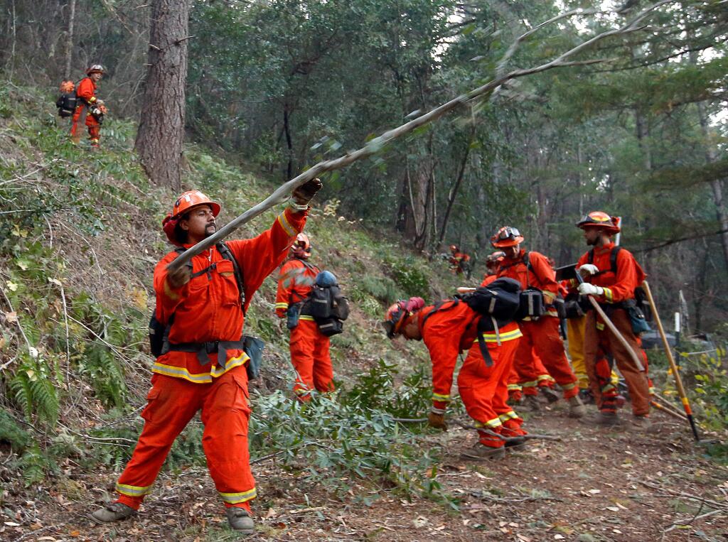 Arthur Ortega and the inmates of Cal Fire Parlin Fork crews 1 and 4 cut a wide fire break above a group of homes along Van Arsdale Road while the Redwood Complex fire burns along the hill above them, in Potter Valley, California on Friday, October 13, 2017. 'My son saw me being taken to jail. Now he can see I'm here doing something good,' says Ortega, who has been working on the fire line with his crew since the start of the Redwood Complex fire. (Alvin Jornada / The Press Democrat)