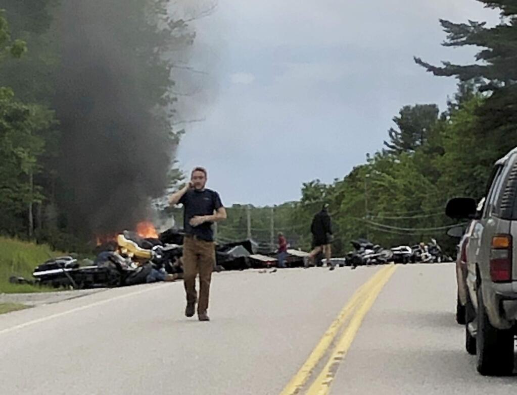 This photo provided by Miranda Thompson shows a man talking on his cellphone at the scene where several motorcycles and a pickup truck collided on a rural, two-lane highway Friday, June 21, 2019 in Randolph, N.H. New Hampshire State Police said a 2016 Dodge 2500 pickup truck collided with the riders on U.S. 2 Friday evening. The cause of the deadly collision is not yet known. The pickup truck was on fire when emergency crews arrived. (Miranda Thompson via AP)