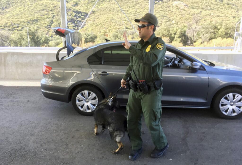 In this Thursday, Dec. 14, 2017, photo, a border patrol agent stops a vehicle at a checkpoint in Pine Valley, Calif. The state legalizes marijuana for recreational use on Monday, Jan. 1, 2018, but that won't stop federal agents from seizing small amounts on busy freeways and backcountry highways. Marijuana possession will continue to be prohibited at eight Border Patrol checkpoints in California, a reminder that state and federal law collide when it comes to pot. (AP Photo/Elliot Spagat)