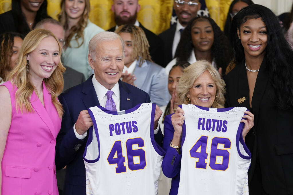 President Joe Biden and first lady Jill Biden are presented with jerseys by LSU women's basketball team captains Angel Reese, right, and Emily Ward, left, during an event to honor the 2023 NCAA national championship team in the East Room of the White House, Friday, May 26, 2023, in Washington. (AP Photo/Evan Vucci)