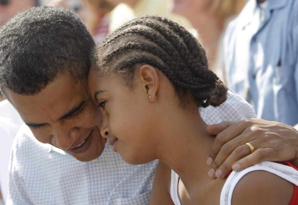 FILE - In this July 4, 2008 file photo, then-Democratic presidential candidate, Sen. Barack Obama, D-Ill. talks to his daughter Malia as they watch an Independence Day parade in Butte, Mont. President Barack Obama's daughter Malia was just 10 and longing for a promised puppy when her family moved into the White House.She's marked some of life's milestones in the past seven years, and another one comes Friday: graduation from high school. (AP Photo/Jae C. Hong, File)
