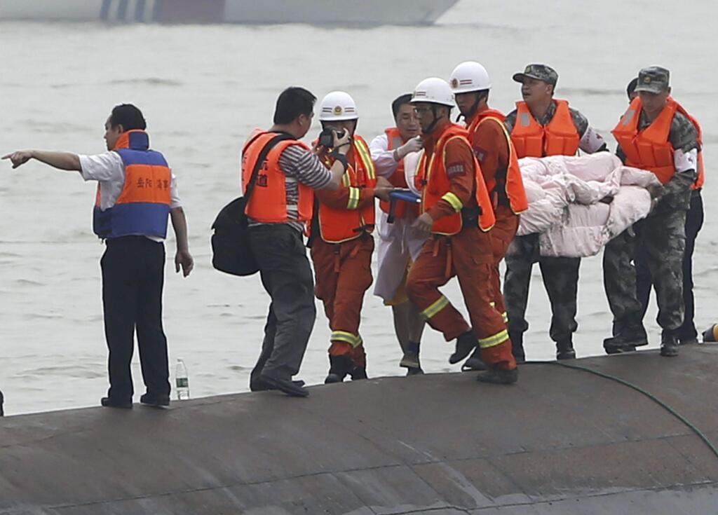 Rescuers carry a survivor pulled from the capsized cruise ship on the Yangtze River in Jianli in central China's Hubei province Tuesday June 2, 2015. Divers on Tuesday pulled survivors from inside the overturned cruise ship, state media said, giving some small hope to an apparently massive tragedy with well over 400 people still missing on the river. (Chinatopix Via AP) CHINA OUT