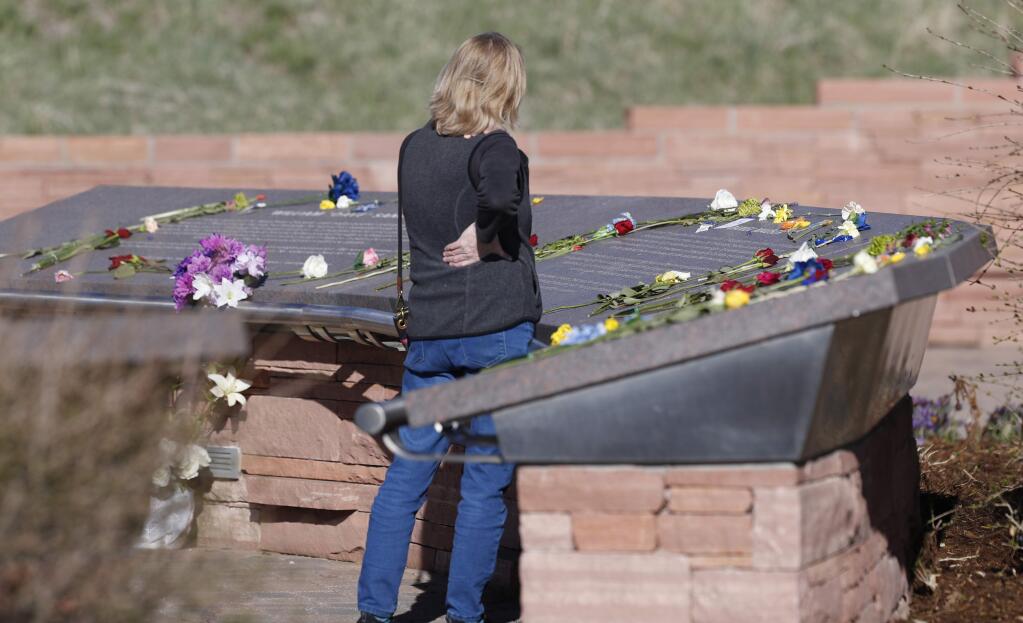 A woman looks over the stories of the slain before a vigil at the memorial for the victims of the massacre at Columbine High School nearly 20 years ago Friday, April 19, 2019, in Littleton, Colo. (AP Photo/David Zalubowski)