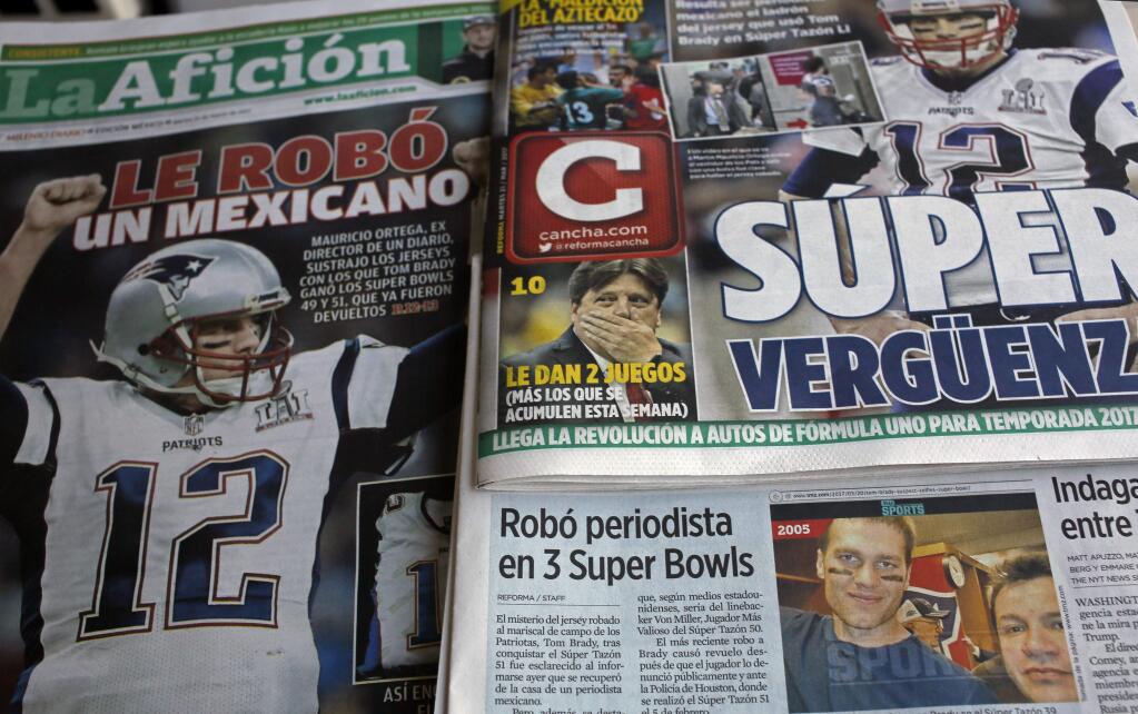 Front pages of Mexican newspapers show headlines and photos about the Tom Brady Superbowl jersey that was allegedly stolen by a Mexican journalist, bottom left on a selfie with Brady, in Mexico City, Mexico March 21, 2017. The headlines read in Spanish 'Super embarrassment' top right and 'Was stolen by a Mexican,' left. (AP Photo/Enric Marti)