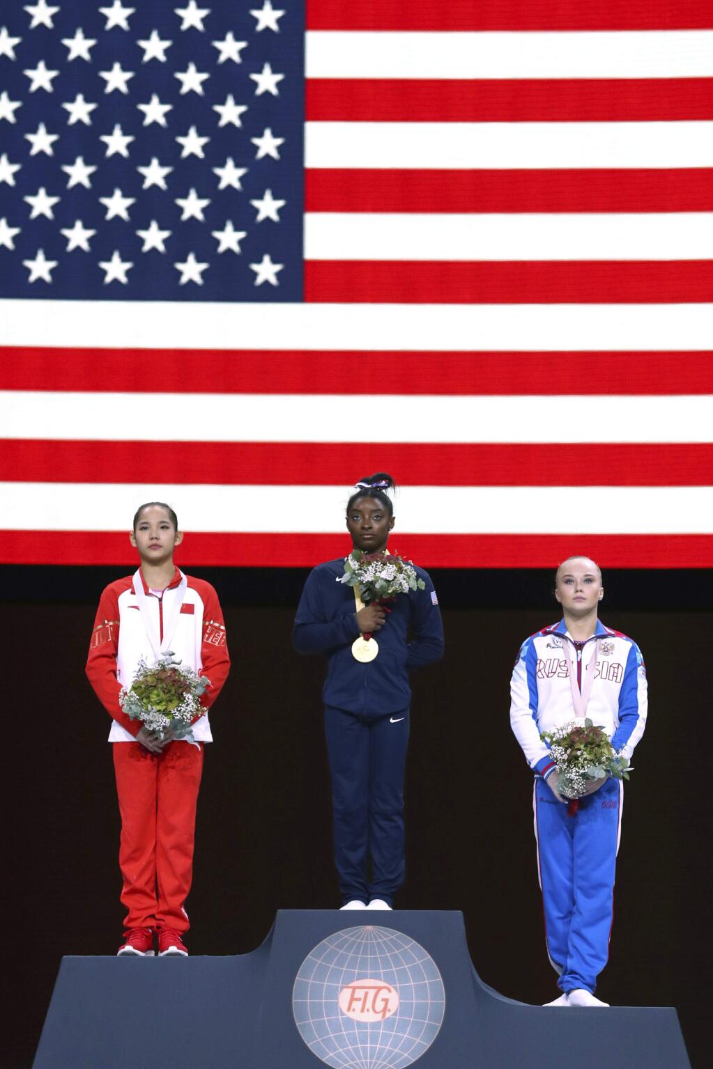 Gold medal winner Simone Biles of the U.S., center, second placed Xijing Tang of China, left, and third placed Angelina Melnikova of Russia celebrate on the podium after the women's all-around final at the Gymnastics World Championships in Stuttgart, Germany, Thursday, Oct. 10, 2019. (AP Photo/Matthias Schrader)