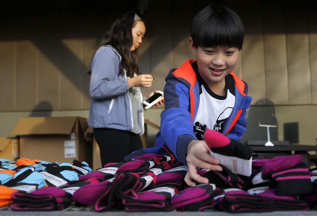 Dylan King, 10, and his sister Lily, 12, who both lost their home in the Tubbs fire, volunteer at a sock give away for fire victims organized by Chuck Pinnow at Orchard Supply Hardware on Thursday, December 28, 2017 in Santa Rosa, California . (BETH SCHLANKER/The Press Democrat)