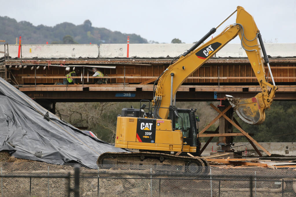 Construction workers build an overpass on Hwy 101 for the future Rainier Avenue extension in Petaluma, Calif., on Tuesday, Jan. 26, 2021. (BETH SCHLANKER/THE PRESS DEMOCRAT)