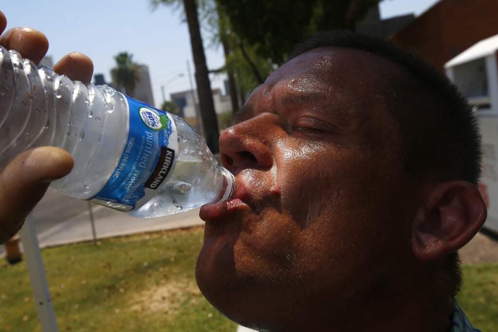 Steve Smith takes a drink of water as he tries to keep hydrated and stay cool as temperatures climb to near-record highs, Monday, June 19, 2017, in Phoenix. (AP Photo/Ross D. Franklin)