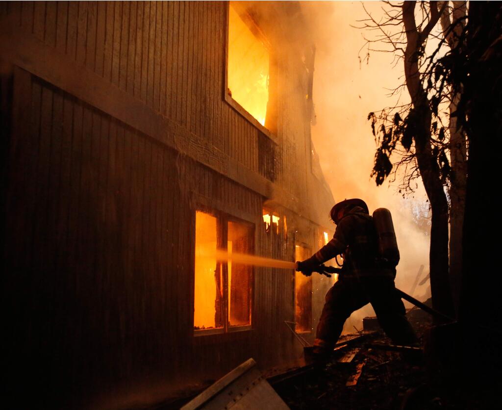 A Gold Ridge firefighter battles a fire in a tri-level home on fire off Burgundy Way in Sebastopol, California on Thursday, September 21, 2017. (Alvin Jornada / The Press Democrat)
