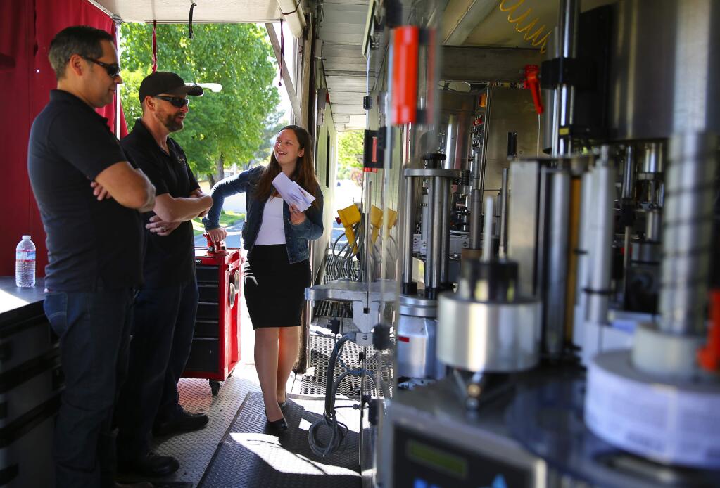 Healdsburg High School student Bailey Esposti, right, talks with Guy Peatow and Jose Molina, of Jackson Family Wines, in a mobile bottling unit during the Career Technical Education Foundation Sonoma County event, at the Sonoma County Fairgrounds in Santa Rosa on Thursday, April 27, 2017. (Christopher Chung / The Press Democrat)