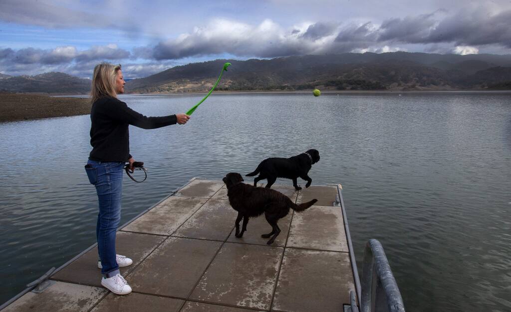 Kristin Groessl of Ukiah throws a ball for her dog at Lake Mendocino where water managers will impound up to 3.8 billion extra gallons of water this winter in the first-ever test of a program that relies on advanced weather forecasting. (JOHN BURGESS/ PD)