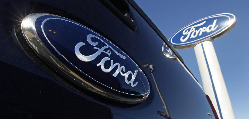 FILE - A Ford logo, on the tailgate of a 2012 F350 Super Duty pick-up truck, and Ford dealership sign are displayed at Salem Ford in Salem, N.H., on Oct. 25, 2011. Ford Motor Company on Tuesday,May 24, 2022, settled claims by 40 U.S. state attorneys general that the company made misleading claims about the fuel economy and payload capacity of some of its vehicles, violating state consumer protection laws. (AP Photo/Charles Krupa, File)