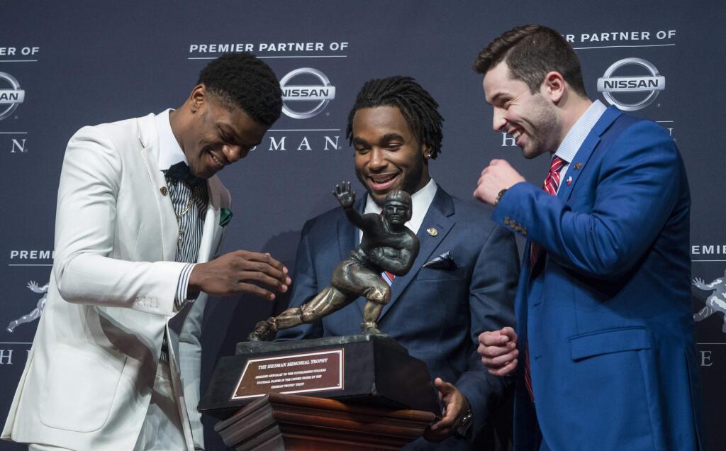 Heisman Trophy finalists, from left, Louisville quarterback Lamar Jackson, Stanford running back Bryce Love and Oklahoma quarterback Baker Mayfield look at the trophy during a media event Saturday, Dec. 9, 2017, before the final selection in New York. (AP Photo/Craig Ruttle)