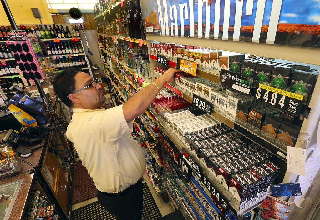 Amarjeet Saggu owner of Ray's Food Center, restocks cigarettes at his Santa Rosa convenience store. (JOHN BURGESS / The Press Democrat)
