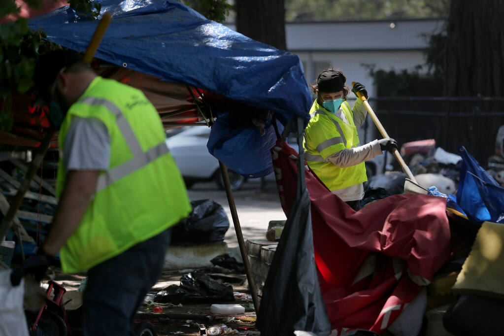 Santa Rosa City public works employees clear a homeless encampment on Roberts Avenue in Santa Rosa, Calif., on Wednesday, April 21, 2021. (Beth Schlanker/ The Press Democrat)