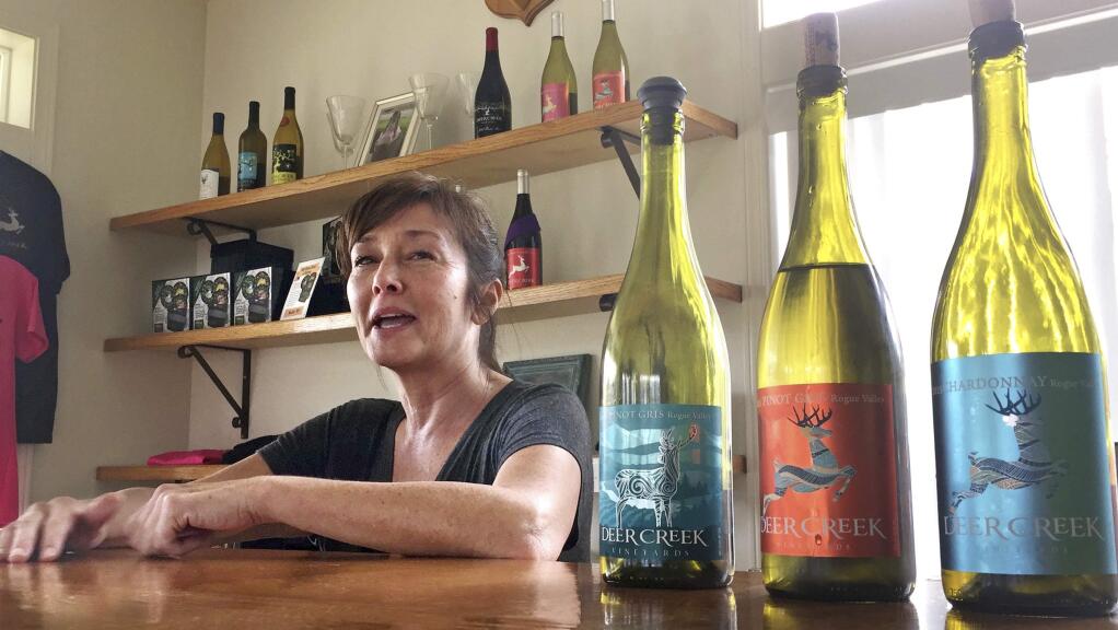 In this April 5, 2017 photo, vineyard owner Katherine Bryan laughs as she discusses the wines available for tasting at Deer Creek Vineyards in Selma, Ore. Bryan is one of a handful of vineyard owners and winemakers in this fertile corner of southwestern Oregon who are branching out into marijuana farming after the legalization of recreational weed in Oregon two years ago. (AP Photo/Gillian Flaccus)