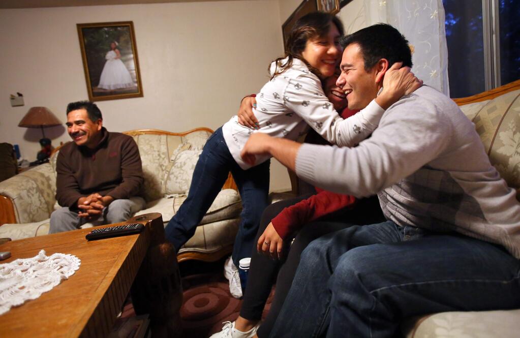 Jose Bedolla, right, and his sister, Jeanette, are hugged Thursday by their mother, Marina, as they react with joy, with their father Robert, at their home in Healdsburg while watching President Barack Obama's announcement of his broad executive action to offer temporary relief from deportation to millions of undocumented immigrants. (Christopher Chung / The Press Democrat)