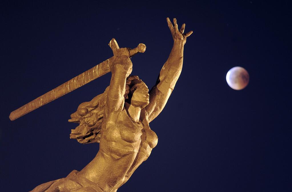 A blood moon rises next to the statue of Nike, the goddess of victory, during a complete lunar eclipse in Warsaw, Poland, Friday, July 27, 2018. Skywatchers around much of the world are looking forward to a complete lunar eclipse that will be the longest this century. (AP Photo/Alik Keplicz)