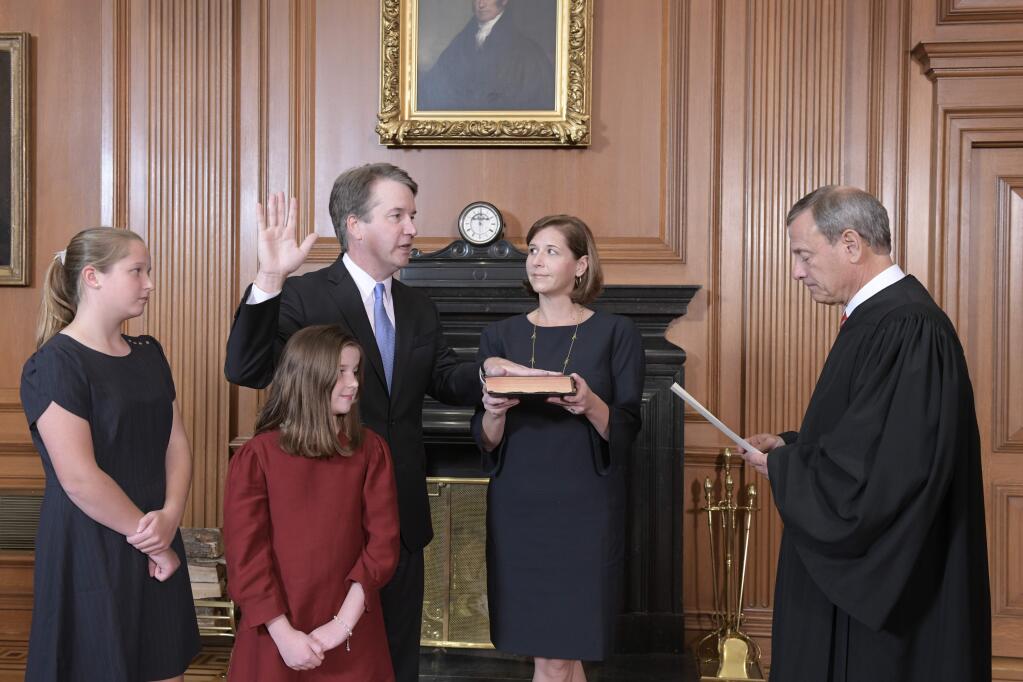 Chief Justice John Roberts, right, administers the Constitutional Oath to Judge Brett Kavanaugh in the Justices' Conference Room of the Supreme Court Building. Ashley Kavanaugh holds the Bible. In the foreground are their daughters, Margaret, left, and Liza. (Fred Schilling/Collection of the Supreme Court of the United States via AP)