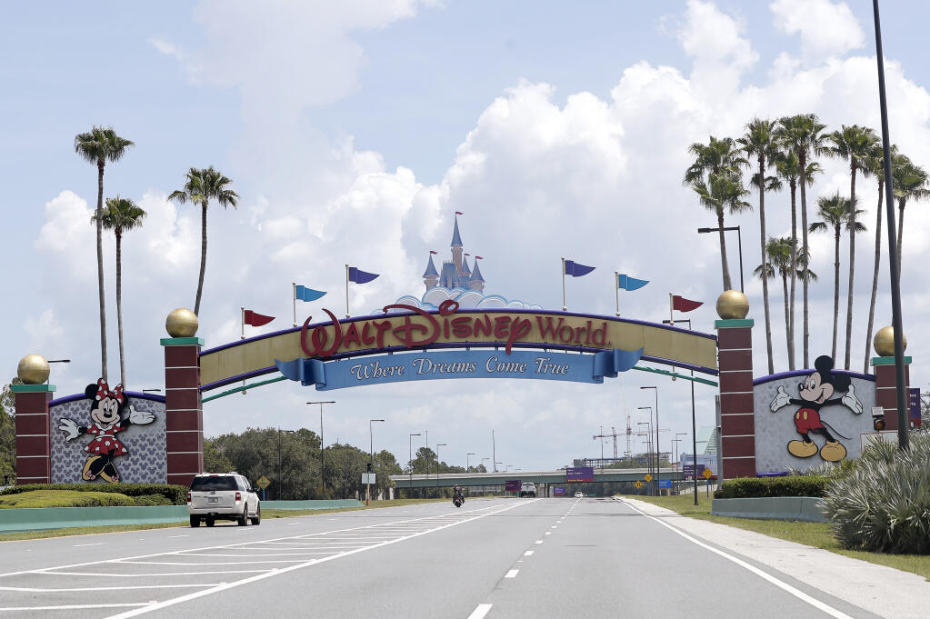 Cars drive under a sign greeting visitors near the entrance to Walt Disney World, Thursday, July 2, 2020, in Lake Buena Vista, Fla. Despite a huge surge of Floridians testing positive for the new coronavirus in recent weeks, Magic Kingdom and Animal Kingdom, two of Disney World's four parks are reopening Saturday, July 11. When they do, visitors to “The Most Magical Place on Earth” will find new rules in place. (AP Photo/John Raoux)