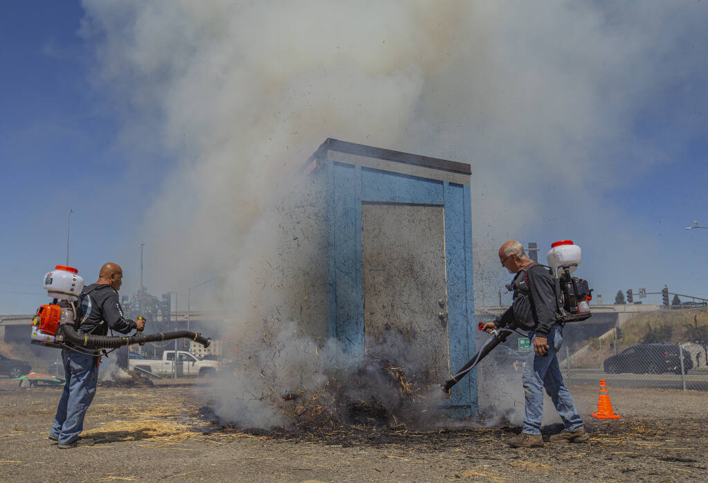 Willy Gonzalez, left, and Mitch Boxwell mist a mixture of water and fire inhibitor solution to knock out flames during a demonstration of their Mighty Fire Breaker MFB-31-CitroTech fire inhibitor at the Wildfire Depot in Rohnert Park, July 21, 2022. (Chad Surmick / Press Democrat)