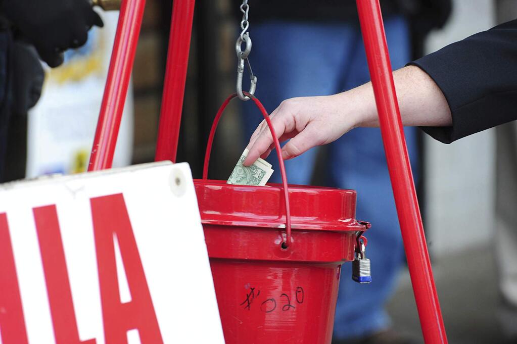FILE - In this Nov. 22, 2017, file photo, a patron donates money in a Salvation Army red kettle in Wilkes-Barre, Pa. In this season of giving, charity seems to be getting an extra jolt because the popular tax deduction for charitable donations will lose a lot of its punch. (Mark Moran/The Citizens' Voice via AP)