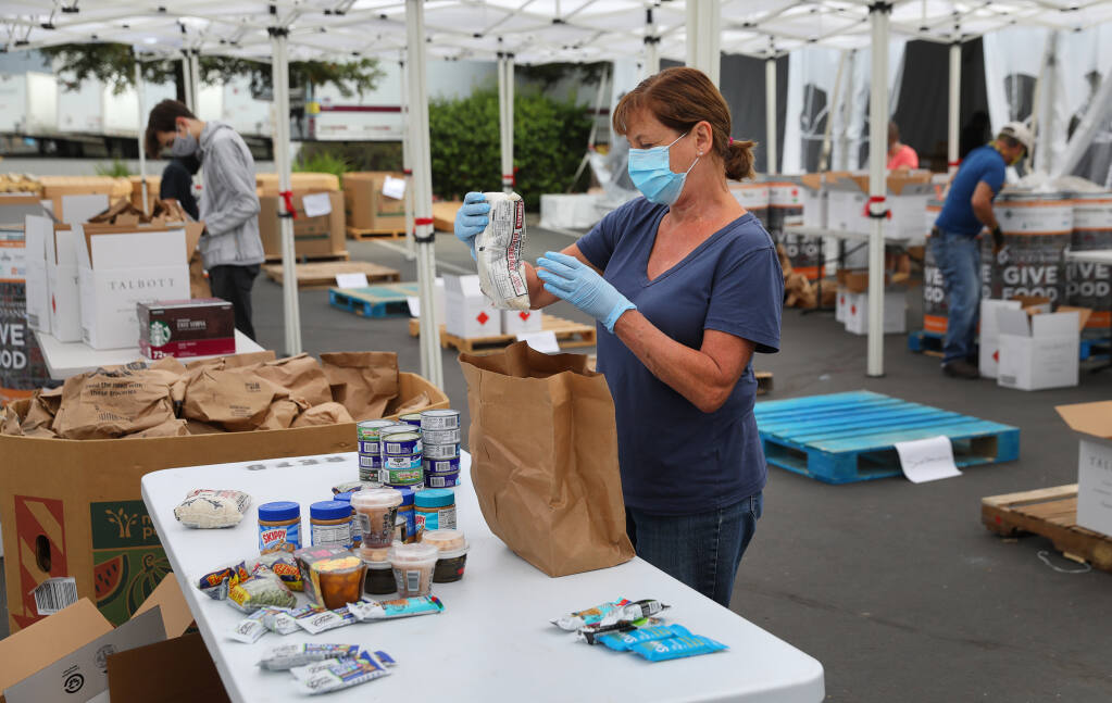 Volunteer Jeanne DeLario sorts food donated to the Redwood Empire Food Bank in Santa Rosa on Friday, July 17, 2020.  (Christopher Chung / The Press Democrat)