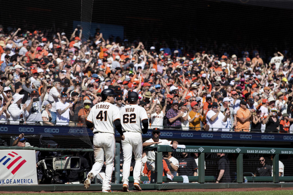 San Francisco Giants' Logan Webb (62) and Wilmer Flores celebrate after scoring against the San Diego Padres in the third inning of a baseball game in San Francisco, Sunday, Oct. 3, 2021. (AP Photo/John Hefti)