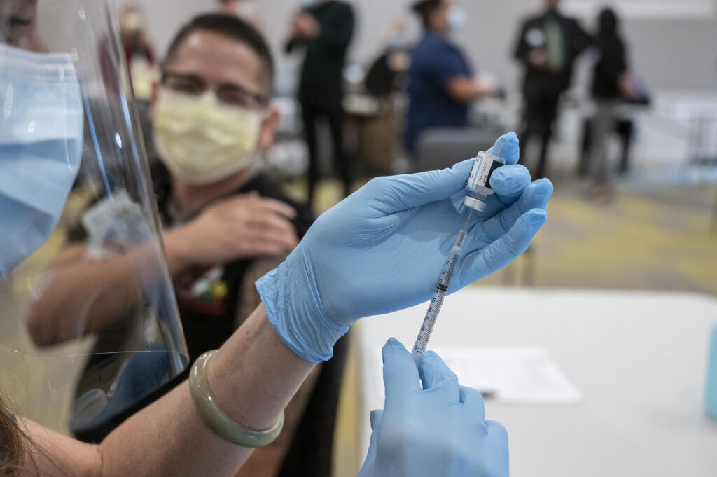 Claudio Alvarado, left, a registered nurse at UC Davis Medical Center, waits to be inoculated with the Pfizer-BioNTech Covid-19 vaccine by Heather Donaldson, registered nurse at UC Davis Medical Center, Tuesday, Dec. 15, 2020 in Sacramento, Calif. (AP Photo/Hector Amezcua, Pool)