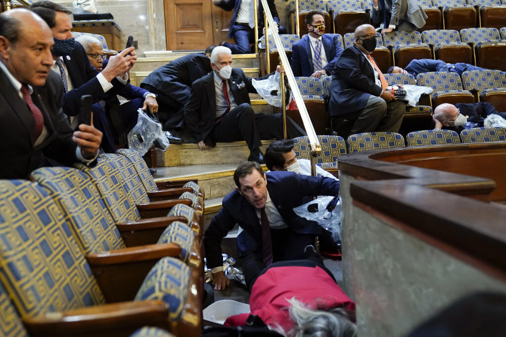 People shelter in the House gallery as protesters try to break into the House Chamber at the U.S. Capitol on Wednesday, Jan. 6, 2021, in Washington. (Andrew Harnik / Associated Press)