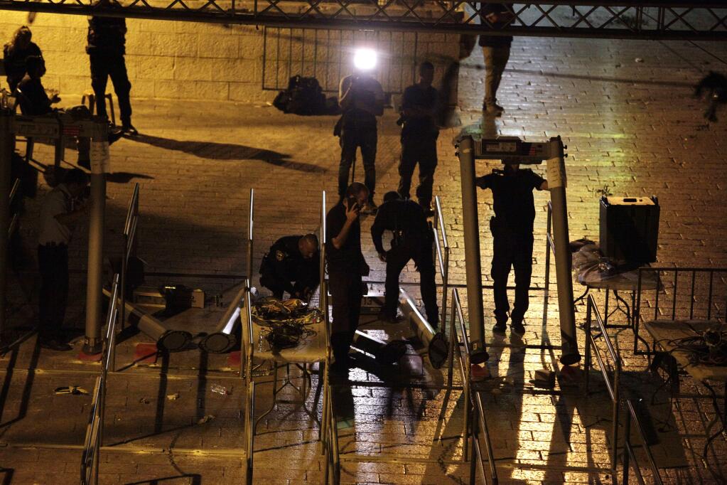Israeli police officers dismantle metal detectors outside the Al Aqsa Mosque compound in Jerusalem's Old City, early Tuesday, July 25, 2017. Israel's security cabinet has decided to remove metal detectors set up at the entrance to a Jerusalem holy site which had angered Muslims. (AP Photo/Mahmoud Illean)