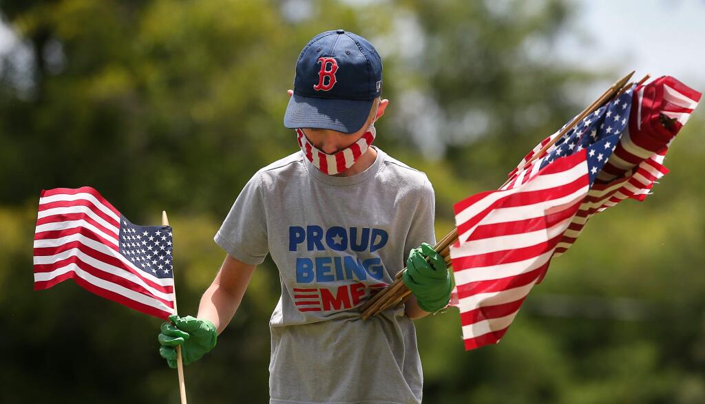 Willy Moessing, 8, looks for the graves of veterans to place flags on for Memorial Day at Santa Rosa Memorial Park, in Santa Rosa on Friday, May 22, 2020. (Christopher Chung/ The Press Democrat)