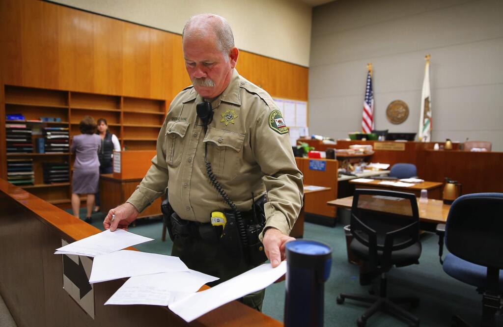 Christopher Chung / The Press DemocratRetired Sonoma County Sheriff's Deputy Charlie Bone, 62, goes over the day's calendar while serving as a bailiff in Sonoma County Superior Courtroom 3 on April 4 in Santa Rosa.