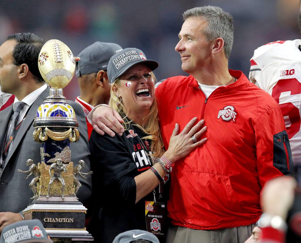 In this Jan. 1, 2016, file photo, Ohio State head coach Urban Meyer hugs his wife, Shelley, after their 44-28 win over Notre Dame in the Fiesta Bowl in Glendale, Ariz. Ohio State placed Meyer on paid administrative leave Wednesday, Aug. 1, 2018, while it investigates claims that his wife knew about allegations of abuse against former Buckeyes assistant Zach Smith, who was fired last week. (AP Photo/Rick Scuteri, File)