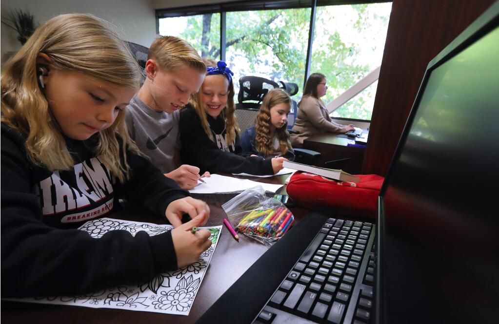 Audrey Caron, left, 8, Zach Henschel, 11, Cali Henschel, 9, and Ella Caron, 10, occupy themselves in Jasmine Caron's office, at Amy Young Bookkeeping, in Santa Rosa on Tuesday, November 13, 2018. The childrens' schools, Matanzas Elementary and Spring Creek Elementary, were closed due to smoke from the Camp fire in Butte County.(Christopher Chung/ The Press Democrat)