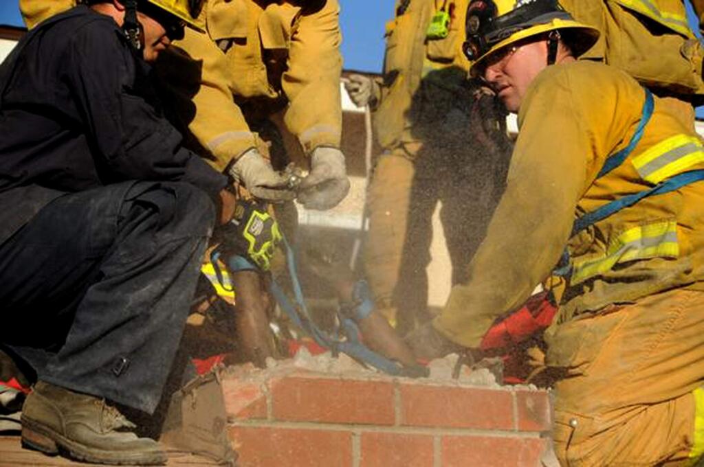 In this Sunday, Oct. 19, 2014 photo provided by the Ventura County Fire Department, firefighters work to free Genoveva Nunez-Figueroa, 30, from a chimney after she became stuck trying to enter a home in Thousand Oaks, Calif. Firefighters had to chisel away much of the chimney and lubricate it with dish soap to free her. (AP Photo/Ventura County Fire Department)