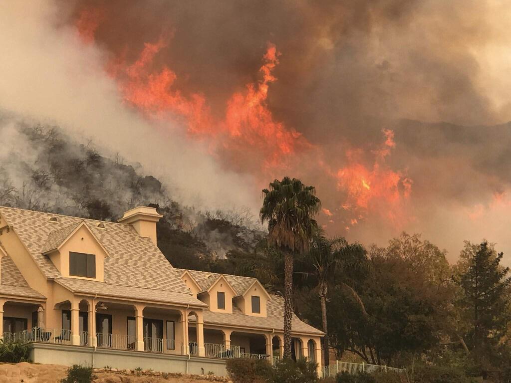 In this Thursday, Dec. 14, 2017, photo provided by the Santa Barbara County Fire Department, shows flames from a back firing operation underway rise behind a home off Ladera Ln near Bella Vista Drive in Santa Barbara, Calif. Red Flag warnings for the critical combination of low humidity and strong winds expired for a swath of Southern California at midmorning but a new warning was scheduled to go into effect Saturday in the fire area due to the predicted return of winds. The so-called Thomas Fire, the fourth-largest in California history, was 35 percent contained after sweeping across more than 394 square miles (1,020 sq. kilometers) of Ventura and Santa Barbara counties since it erupted Dec. 4 a few miles from Thomas Aquinas College. (Mike Eliason/Santa Barbara County Fire Department via AP)