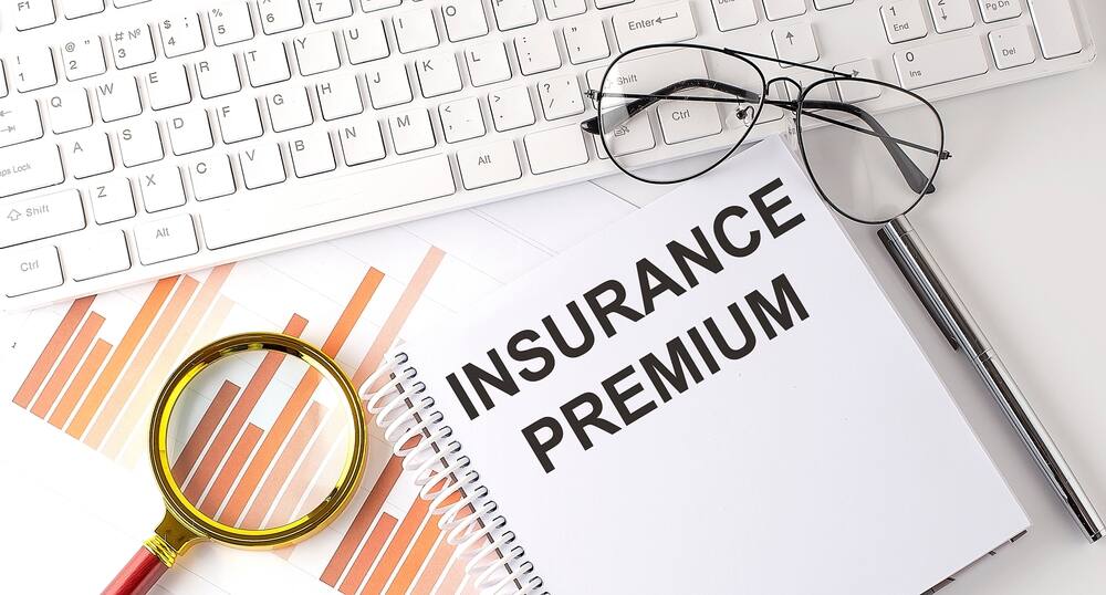 INSURANCE PREMIUM text written on notebook with keyboard, chart,and glasses