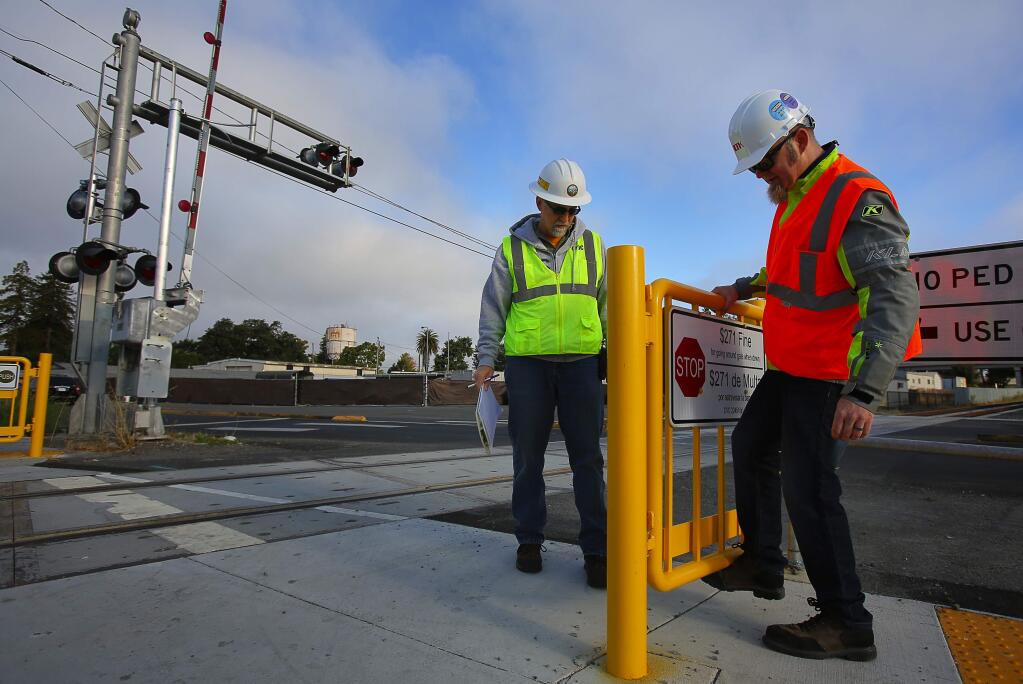 California Public Utilities Commission Safety and Enforcement Division utitilites engineer Dave Stewart, left, and Aaron Parkes, systems consultant with LTK Engineering Services look over a pedestrian exit gate at the rail crossing, at Sebastopol Road, in Santa Rosa, on Friday, August 12, 2016. (Christopher Chung/ The Press Democrat)