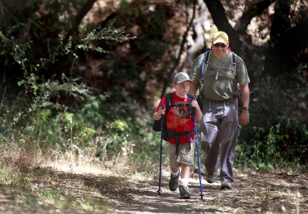 Ari Castaneda, 8, and his dad, Paul, hike towards an overnight campground where they will be spending the night at Hood Mountain Regional Park in Kenwood, on Monday, July 28, 2014. (BETH SCHLANKER/ The Press Democrat)