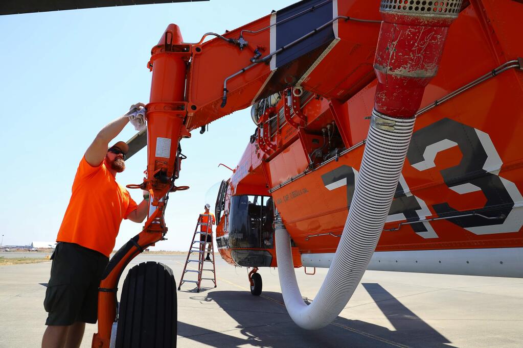 Erickson, Inc., mechanic Brandon DeFord helps to clean Helitanker 743 at Cal Fire's Sonoma Air Attack base, in Santa Rosa on Monday, August 7, 2017. (Christopher Chung/ The Press Democrat)