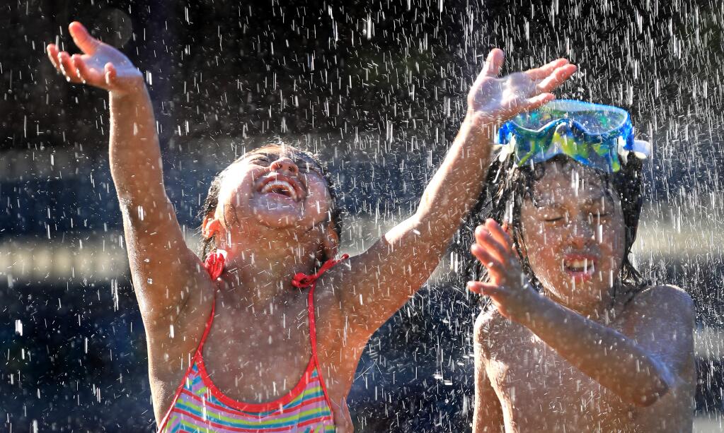 Rebecca and Logan Velez, 8 and 6, take in the high temperatures with a run through the fountains at Fish Park in downtown Santa Rosa on Tuesday, April 23, 2019. (KENT PORTER/ PD)