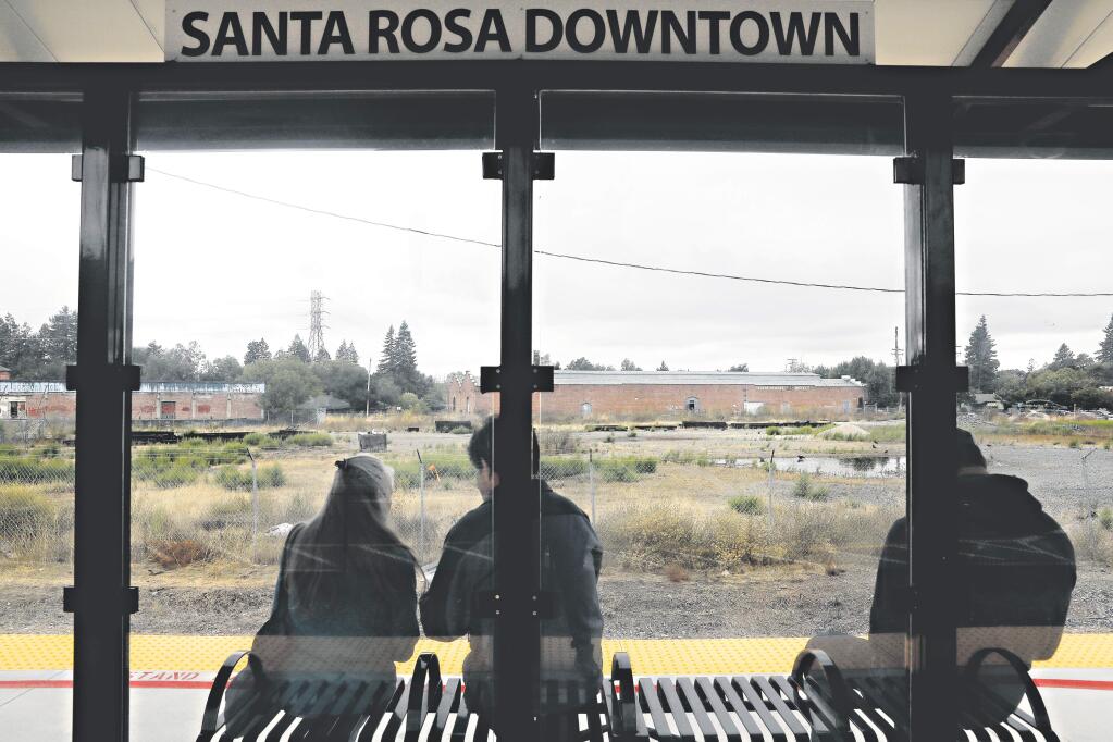 People wait at the downtown SMART station which is across the tracks from a 5-acre piece of property for sale in Santa Rosa on Thursday, October 4, 2018. (Beth Schlanker/ The Press Democrat)