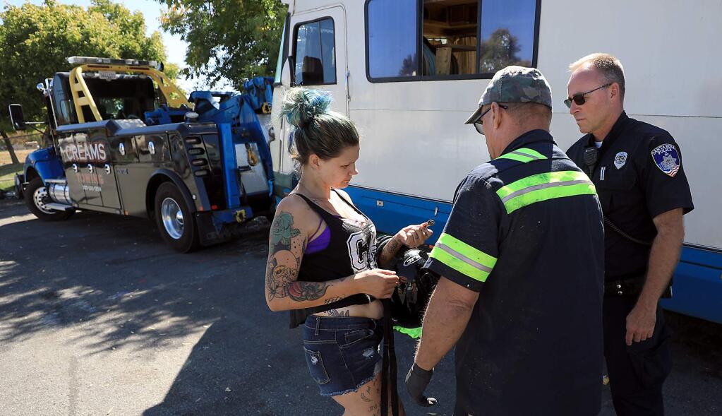 Crystal Dunigan hands the key to Dave Myers of Creams towing as her motorhome is towed from Challenger Way, Wednesday, Sept. 19, 2018 in Santa Rosa. At right is Santa Rosa police vehicle abatement officer Sean Wall. (Kent Porter / Press Democrat) 2018